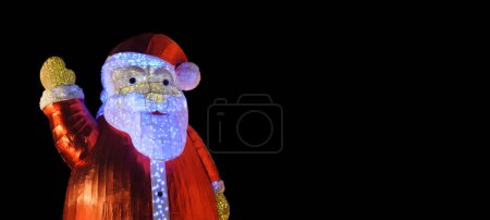 Téléchargez les photos : Gros plan d'une Santa Clause sur fond noir opaque. Salut de Noël. Espace de copie. - en image libre de droit