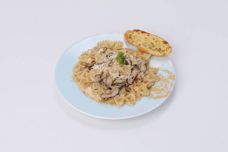 Téléchargez les photos : Farfalle pâtes avec sauce à la crème blanche champignon et pain à l'ail dans un plat sur un fond isolé - style culinaire italien - en image libre de droit
