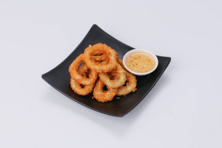 Téléchargez les photos : Homemade crunchy fried onion rings with sweet sauce in a black dish on white background. - en image libre de droit