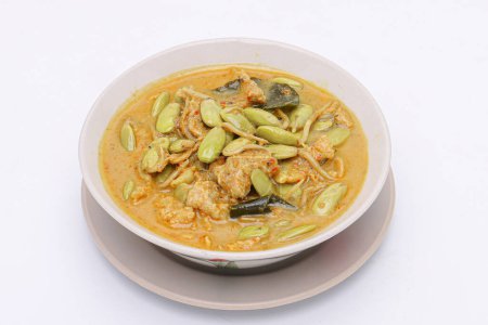 Téléchargez les photos : Curry jaune épicé au porc et Parkia timoriana. Délicieux chaud et épicé, style thaïlandais du sud dans un bol sur un fond blanc isolé. De la nourriture thaïlandaise. Vue du dessus. - en image libre de droit
