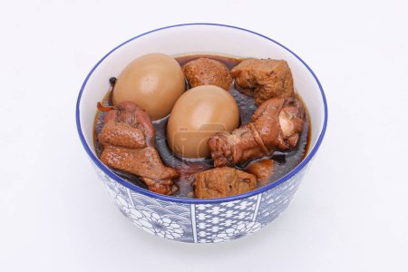 Téléchargez les photos : Œufs et poulet en sauce brune douce ou Kai Pa Lo en thaï dans un bol sur un fond blanc isolé. De la nourriture thaïlandaise. Vue du dessus. - en image libre de droit