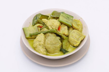 Téléchargez les photos : Le curry vert avec des boules de poisson à l'aubergine et au lait de coco de noix de coco fraîche est un plat thaïlandais célèbre. boule de poisson en sauce épaisse à la noix de coco. dans un bol sur fond isolé. Vue du dessus. - en image libre de droit