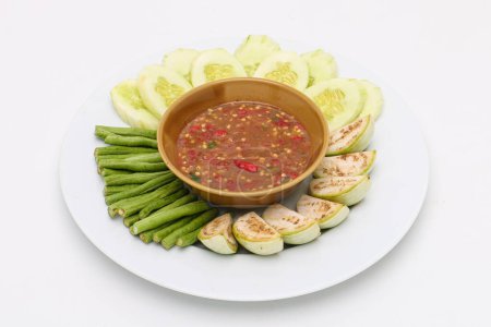 Téléchargez les photos : Pâte de crevettes sauce chili (Nam Prik Ka Pi) servir avec du concombre frais, brinjals verts frais, et des haricots longs frais, nourriture thaïlandaise sur fond isolé. - en image libre de droit