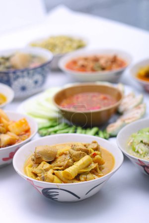 Téléchargez les photos : Soupe aigre du Sud avec du poulet et des pousses de bambou conservées dans un bol sur l'ensemble des assiettes de groupe nourriture thaïlandaise. Nourriture thaï-méridionale. Vue de dessus. vertical - en image libre de droit