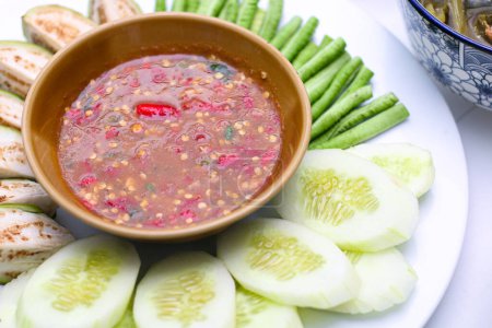 Téléchargez les photos : Pâte de crevettes sauce chili (Nam Prik Ka Pi) servir avec du concombre frais, brinjals verts frais, et des haricots longs frais, nourriture thaïlandaise sur fond isolé. - en image libre de droit