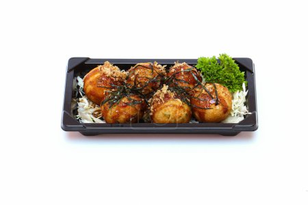 Téléchargez les photos : Takoyaki, mayonnaise, sauce soja, saupoudrée d'algues dans une assiette noire sur fond blanc. - en image libre de droit