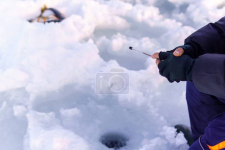 Photo for Person holding a small fishing rod in the snow. Selective focus. Copy space - Royalty Free Image