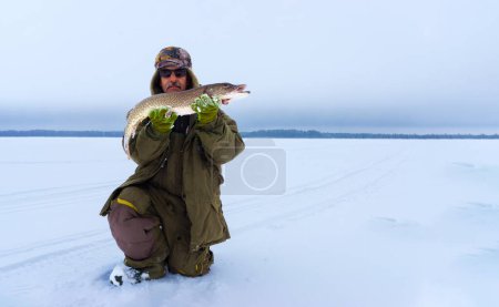 Photo for Man Holding a Fish in the Snow. Winter fishing, adventure. Banner, copy space - Royalty Free Image