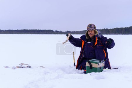 Téléchargez les photos : Un homme tenant un poisson entre les mains. Pêche d'hiver. Bannière, espace de copie - en image libre de droit