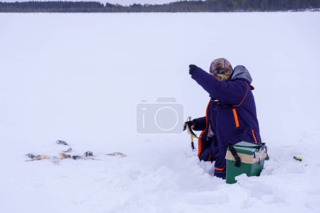Téléchargez les photos : Un homme tenant un poisson dans la neige. Pêche d'hiver, aventure. Bannière, espace de copie - en image libre de droit