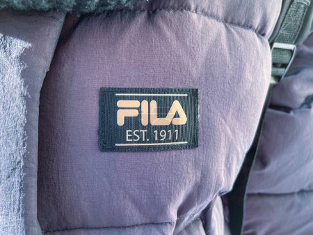 Foto de Tyumen, Rusia-11 de enero de 2024: Logotipo de la marca Fila en un tejido púrpura, mostrando el prominente FILA EST. 1911 - Imagen libre de derechos