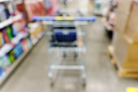 Blurry shot of a shopping cart in a busy store aisle, showcasing the hustle and bustle of shopping activities.