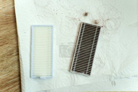 Saugroboter beleuchten das Haus und zeigen den Kontrast zwischen einem sauberen Filter und einem gebrauchten, staubbeladenen Filter