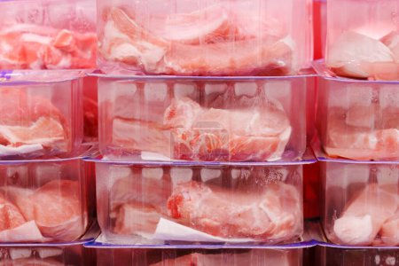 Plastic containers filled with various cuts of meat, ready for processing or distribution in a food industry setting.