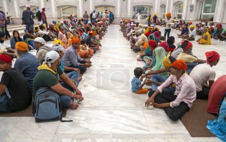 Foto de NEW DELHI - SEPTEMBER 18: People sitting on the floor and waiting for the free food at Gurudwara Bangla Sahib Sikh house of worship in Delhi, on September 18. 2022 in India - Imagen libre de derechos