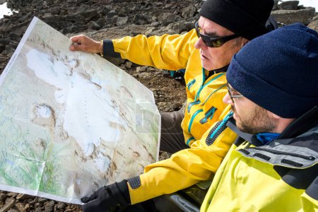 Foto de Dos hombres con mapa explorando el desierto en la aceleración del trekking. Guía de montaña en busca de sendero a través del paisaje. Ok vulcano, Islandia - 26 Julio 2015 - Imagen libre de derechos