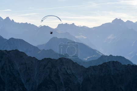 Foto de Parapente sobre las montañas azules Silhouette, Allgaeu, Oberstdorf, Alpes, Alemania. Destino de viaje. Concepto de verano y vacaciones. - Imagen libre de derechos