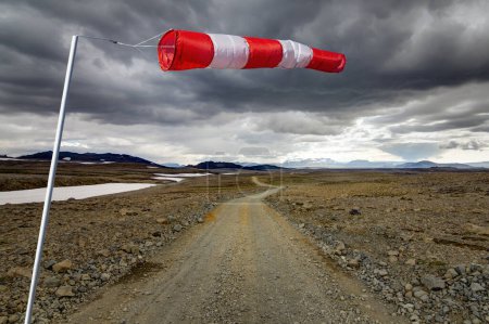 Foto de Windsack with red stripes and a long road leads through the vastness of the landscape to the horizon. Kaldidalur, Iceland. Concept for Prediction and Vision for new and creative business solutions. - Imagen libre de derechos
