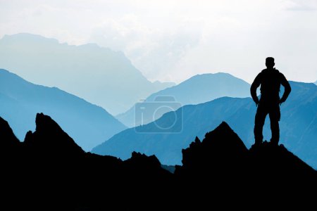 Foto de Happy winning successful silhouette hiker or climber at sunrise standing relaxed and is happy for having reached mountain top summit goal during alpine hiking and climbing adventure travel. Tirol - Imagen libre de derechos