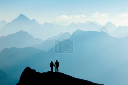Foto de Couple in love standing on mountain peak holding hands. Man and woman enjoying sunrise after successful hiking trip reaching mountain top. Tirol, Austria. Allgau, Bavaria. - Imagen libre de derechos