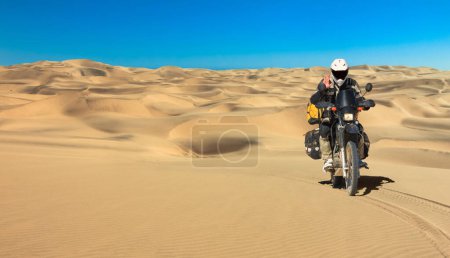Foto de Lonely Motorbiker driving in sand dune desert. Motorcycle Expedition in Namib Desert, Namibia - Imagen libre de derechos