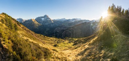Foto de Gran puesta de sol en las montañas. Retroiluminación con bonitas llamaradas de lentes vibrantes y rayos de sol. Alpes, Baviera, Kleinwalsertal, Tirol, Austria. - Imagen libre de derechos