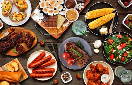 Sommer BBQ Esstisch Szene über einem weißen Holz Banner Hintergrund. Auswahl an gegrilltem Fleisch, Gemüsegerichten und duftenden Platten. Gesamtübersicht.