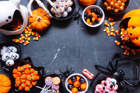 Photo for Halloween trick or treat candy frame. A collection of spooky sweets. Top down view on a dark stone background with copy space. - Royalty Free Image
