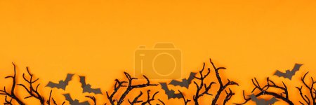 Téléchargez les photos : Halloween bordure inférieure de chauves-souris effrayantes et branches noires. Vue du dessus sur un fond de bannière orange avec espace de copie. - en image libre de droit