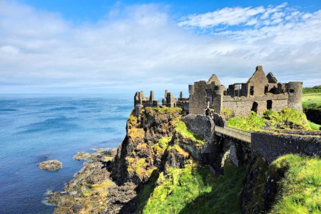 Photo for Ruins of the medieval Dunluce Castle on green cliffs overlooking the North Atlantic ocean. Causeway Coast, Northern Ireland. - Royalty Free Image