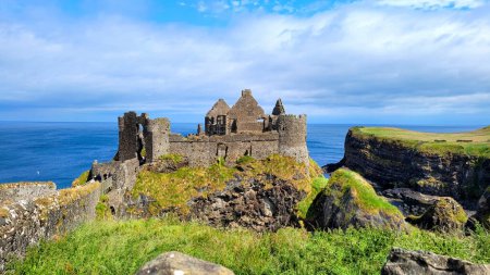 Photo for Ruins of the medieval Dunluce Castle along the green cliffs of the Causeway Coast, Northern Ireland - Royalty Free Image