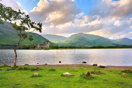 View of Kilchurn Castle on Lock Awe in the highlands of Scotland with lone tree near sunset
