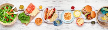 Foto de Barbacoa de verano o escena de mesa de picnic con hamburguesas, perritos calientes, ensalada y aperitivos. Vista superior sobre un fondo de pancarta de madera blanca. - Imagen libre de derechos