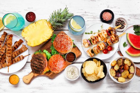 Photo for Summer BBQ food table scene. Hamburgers, meat skewers, potatoes, fruit and snacks. Above view on a white wood background. - Royalty Free Image