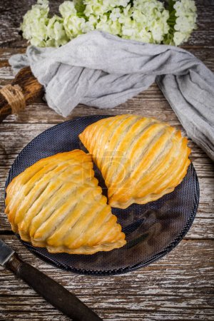 Puff pastry apple pastry turnovers for dessert on a wooden table.