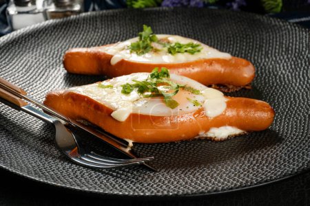Photo for Fried egg in sausages on a black plate. Selective focus. - Royalty Free Image