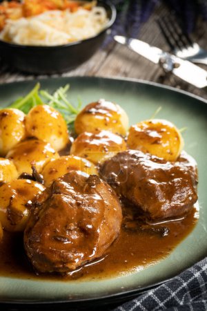 Traditional German braised pork cheeks in brown sauce with mushroom served with silesian dumplings.
