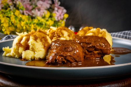 Joues de porc braisées allemandes traditionnelles en sauce brune servie avec purée de pommes de terre.