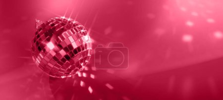 Téléchargez les photos : Boule disco de Noël avec des rayons lumineux et un bokeh coloré sur fond magenta. Couleur de l'année 2023. - en image libre de droit
