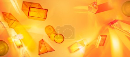Téléchargez les photos : Abstract scene with geometric shapes and light rays on an orange-yellow background. Set of colored transparent geometric forms.Banner - en image libre de droit