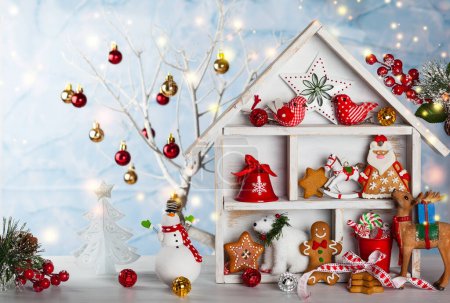 Téléchargez les photos : Scène de Noël avec maison en bois blanc, cadeaux, biscuits, bonhomme de neige et cerfs - en image libre de droit