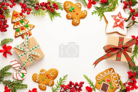 Téléchargez les photos : Fond de Noël avec biscuits au pain d'épice, boîtes-cadeaux et branches de houx avec des baies rouges sur blanc. Concept de nature festive d'hiver. Pose plate, espace de copie. - en image libre de droit