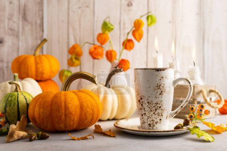 Téléchargez les photos : Nature morte d'automne avec tasse de thé, citrouilles, fleurs et bougies sur la table.. - en image libre de droit