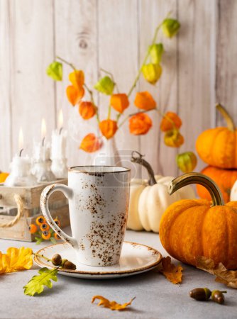 Téléchargez les photos : Nature morte d'automne avec tasse de thé, citrouilles, fleurs et bougies sur la table.. - en image libre de droit