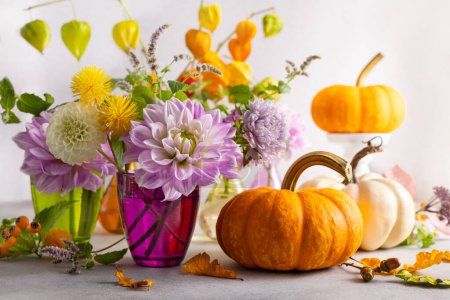 Téléchargez les photos : Nature morte d'automne avec bouquet de fleurs et citrouilles blanches et orange sur la table. Décoration d'automne pour la maison. - en image libre de droit