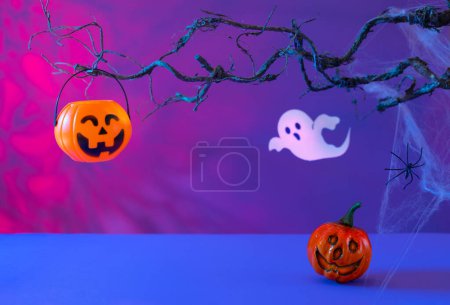 Téléchargez les photos : Décorations d'Halloween avec citrouilles, araignée, toile d'araignée, fantôme et chauve-souris sur fond néon. Concept de fête d'Halloween. - en image libre de droit