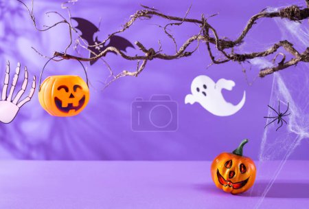 Téléchargez les photos : Décorations d'Halloween avec citrouilles, araignée, toile d'araignée, fantôme et chauve-souris sur fond violet. Concept de fête d'Halloween. - en image libre de droit