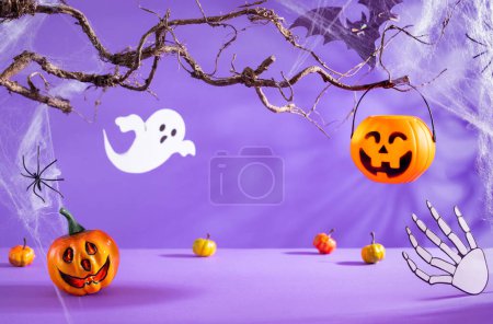 Téléchargez les photos : Décorations d'Halloween avec citrouilles, araignée, toile d'araignée, fantôme et chauve-souris sur fond violet. Concept de fête d'Halloween. - en image libre de droit
