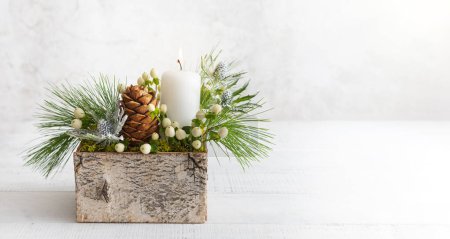 Téléchargez les photos : Composition de Noël de bougie, cônes de pin, branches de sapin, fleurs et baies d'hiver dans une boîte en bois. Confortable maison concept d'hiver. - en image libre de droit