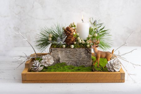 Photo for Christmas composition of candle,deer, pine cones, fir branches, flowers, moss, winter berries in wooden box. Cozy home winter concept. - Royalty Free Image